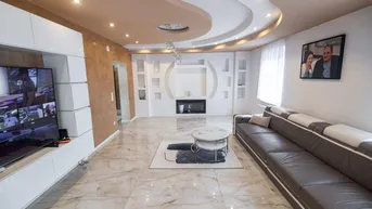 Modernes Wohnzimmer mit stilvoller Deckenbeleuchtung, großem Sofa und integriertem Kamin.