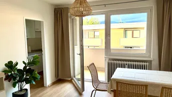 Helles Wohn- und Esszimmer mit Holzboden und direktem Zugang zum Balkon, mit Blick in die Küche.