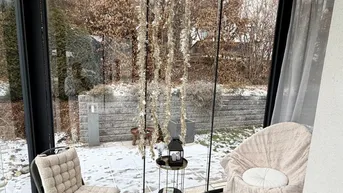 Verglaste Loggia mit Sitzgelegenheiten und Blick auf den verschneiten Garten, ideal zum Entspannen.