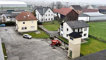 Überblick über das Anwesen mit mehreren Wohnhäusern, Grünflächen und dem angrenzenden Industriegelände.