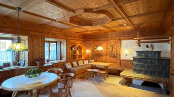 Gemütlicher Wohn- und Essbereich im alpinen Stil mit Holztäfelung und traditionellem Kachelofen.