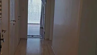 Heller Flur mit Holzfußboden und Einbaustrahlern, der zu weiteren Räumen führt.