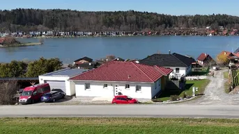 Einfamilienhaus mit rotem Ziegeldach und Seeblick in ländlicher Umgebung.