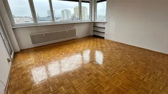 Helles Wohnzimmer mit Parkettboden und weitem Blick auf die Stadtlandschaft durch große Fenster.