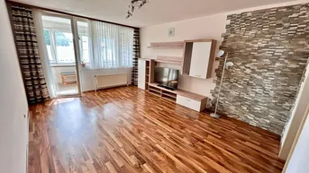 Wohnzimmer mit Laminatboden, moderner Wohnwand und dekorativer Steinwand.