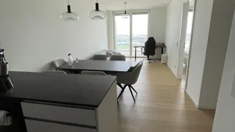 Heller offener Wohn-Essbereich mit moderner Küche, Parkettboden und Zugang zum Balkon.