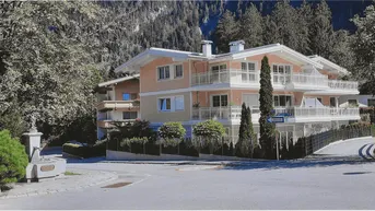 Modernes Mehrfamilienhaus mit mehreren Balkonen und gepflegter Fassade in alpiner Umgebung.
