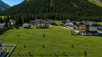 Luftaufnahme von grünen Baugrundstücken mit nummerierten Parzellen und Bergblick in alpiner Umgebung.
