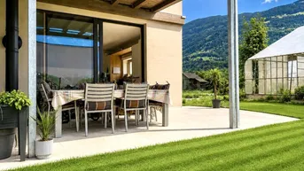 Große Terrasse mit Esstisch, umgeben von Rasen und mit Blick auf die Berge.