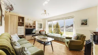 Helles Wohnzimmer mit bequemen Sofas, Parkettboden und großem Fenster mit Bergblick.