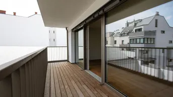 Geräumiger Balkon mit Holzboden und Blick auf die umliegenden Gebäude.