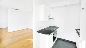 Helle Küchenzeile mit dunkler Arbeitsplatte und Blick in den angrenzenden Wohnbereich.