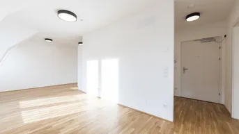 Helles, leeres Zimmer mit Parkettboden, weißen Wänden und Dachschrägen, bereit zur Einrichtung.