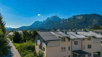 Panoramablick auf ein modernes Wohngebäude mit Photovoltaikanlage und majestätischer Bergkulisse.