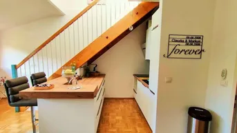 Moderne Küchenzeile mit Holzarbeitsplatte und integrierter Frühstücksbar unter der Treppe.