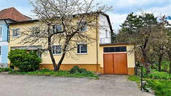 Gelbes Wohnhaus mit blühendem Baum im Vorgarten und integrierter Garage.