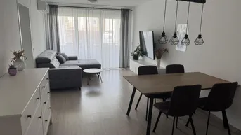 Heller offener Wohn-Essbereich mit modernem Sofa, Esstisch und Zugang zum Balkon.