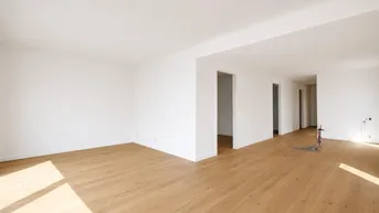 Helles, leeres Zimmer mit Holzboden und weißen Wänden, bereit zur individuellen Gestaltung.