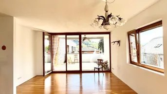 Helles Wohnzimmer mit Parkettboden, Zugang zur Terrasse und Blick auf die umliegende Landschaft.