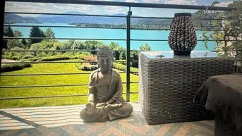 Gemütliche Terrasse mit Buddha-Statue, Korbmöbeln und atemberaubendem Blick auf den See und die Berge.