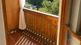 Sonniger Balkon mit Holzbalkon und Fliesenboden, bietet einen schönen Blick ins Grüne.