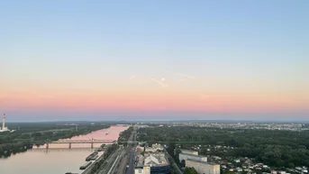 Panoramablick über die Donau und die Stadt bei Sonnenaufgang mit rosa Himmel.