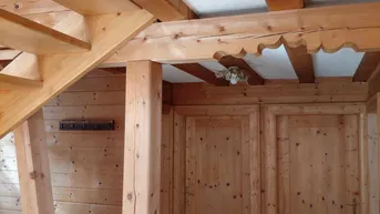 Traditioneller Flur mit Holzvertäfelung, sichtbaren Deckenbalken und rustikaler Holztreppe.