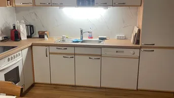Funktionale Küche mit hellen Holzschränken, Arbeitsplatte aus Holz und integrierten Geräten.