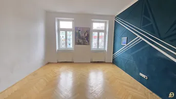 Helles Zimmer mit Fischgrätparkett und einer Wand mit modernem geometrischem Muster.