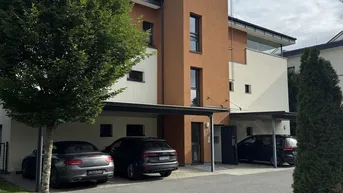 Moderne Wohnanlage mit Carports und gepflegter Außenfassade unter blauem Himmel.