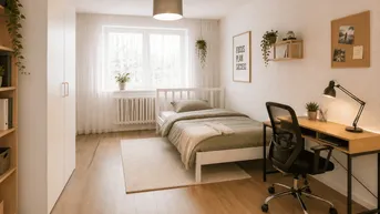 Helles Schlafzimmer mit Holzboden, weißem Bett, Schreibtisch und großem Fenster mit Grünblick.