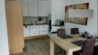 Moderne offene Küche mit weißen Schränken und Essbereich in einem hellen Wohnkonzept.