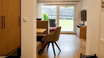 Heller Wohn- und Essbereich mit Holzboden und direktem Zugang zum grünen Garten.