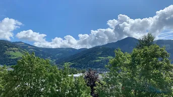 Malerischer Bergblick mit üppiger grüner Vegetation unter blauem Himmel und weißen Wolken.