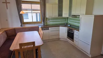 Funktionale Einbauküche mit Essbereich, hellen Schränken und Fensterblick.