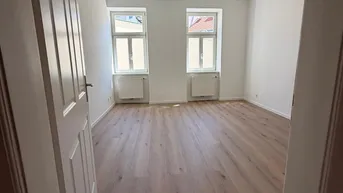 Heller, leerer Wohnraum mit neuem Laminatboden und zwei Fenstern, bereit zur individuellen Gestaltung.