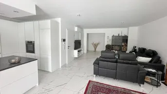 Gemütlicher Wohnbereich mit bequemen Sofas und Blick auf die moderne offene Küche.