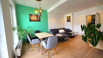 Helles Wohn- und Esszimmer mit modernem Design, grüner Akzentwand und Holzboden.