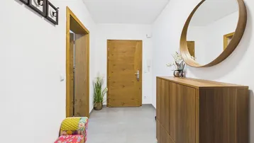 Heller Flur mit Holztüren, Schuhschrank und rundem Wandspiegel.