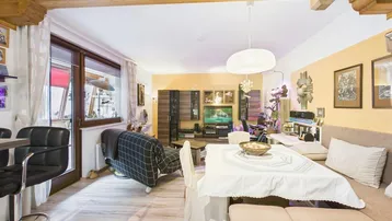 Geräumiger Wohn-Essbereich mit Holzbalkendecke, Parkettboden und Zugang zu einem Balkon.