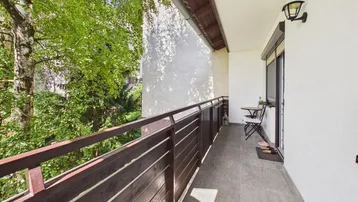 Langer Balkon mit Fliesenboden, Metallgeländer und Blick ins Grüne.