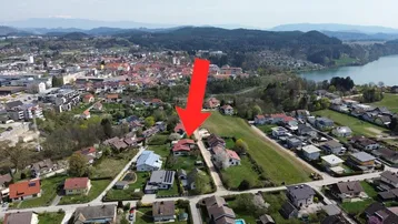 Luftaufnahme einer Wohngegend mit See im Hintergrund und markiertem Grundstück.