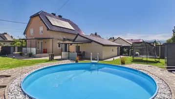 Großer Garten mit rundem Aufstellpool, Trampolin und Photovoltaikanlage auf dem Hausdach.