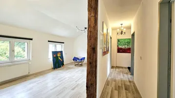 Helles Wohnzimmer mit Holzbalken, modernem Laminatboden und Blick ins Grüne.