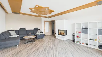 Gemütliches Wohnzimmer mit großem Ecksofa, modernem Kamin und dekorativer Holzdecke.