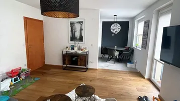 Heller offener Wohnbereich mit Holzboden, moderner Einrichtung und Blick auf den Essbereich.