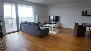 Helles Wohnzimmer mit Parkettboden, großem Fenster und Zugang zum Balkon.
