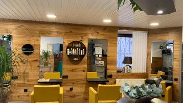 Moderner Friseursalon mit Holzvertäfelung, gelben Stühlen und großen Spiegeln, hell beleuchtet.