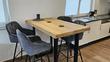 Moderne Küche mit Holztresen, Barhockern und integrierter Spüle unter dem Fenster.