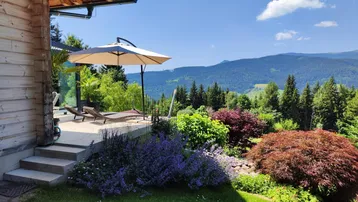 Sonnige Terrasse mit bequemen Liegestühlen und weitem Blick auf die umliegende Berglandschaft.